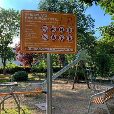 Farblich gestaltetes Spielplatzschild für eine Hausverwaltung, montiert im Außenbereich