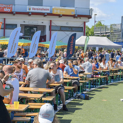 Zuschauer auf Sitzbänken während einer Benefiz-Fußballveranstaltung
