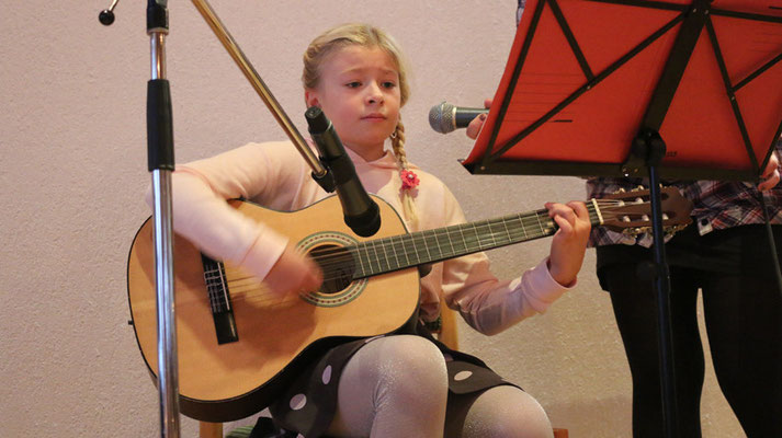 Emmelie (10) spielt auf der Gitarre und begleitet mit Gesang: "Runtergekommen, abgestiegen"