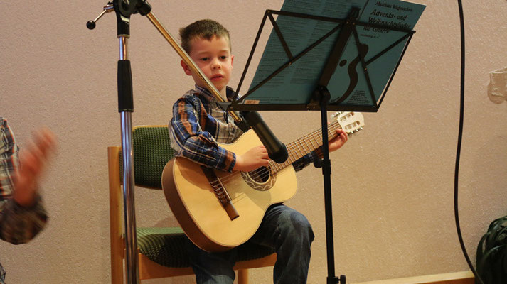 Jonas (6) zupft an der Gitarre "Wir sagen euch an...".