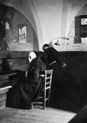 Padre Pio siede in raccoglimento davanti al Crocifisso; accanto a lui padre Onorato Marcucci da San Giovanni Rotondo, suo assistente personale