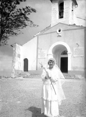 Una ragazza posa per la foto-ricordo in occasione della sua Prima Comunione. Sullo sfondo, la facciata della chiesa di Santa Maria Incoronata del Monte