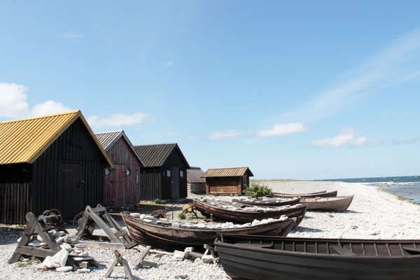 Fischerbuden aus Holz oder gestapelten Steinen mit Bretter- oder Schindeldächern stehen dicht beieinander, die Buden sehen altertümlich aus 