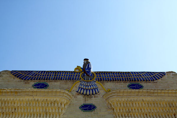Über dem Säulenportal der Eingangsfassade schwebt das aus glasierten Fliesen hergestellte Symbol des Gottes Ahura Mazda.