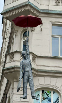 Es gibt aber auch moderne Kunst an den Häusern, wie die Skulptur mit dem Namen "Leichte Unsicherheit": Mann mit Regenschirm und Aktenkoffer über der Straße.