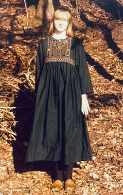 Grünes Kleid mit Spiegelstickerei, Hintergrund Herbstlaub braun