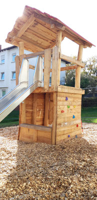 Kletterturm aus massiver Robinie mit Kletterwand und Rutschstange. Unten Spieltresen und Sitzbank.