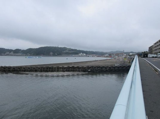 ・渚橋からの逗子海岸  渚橋は、国道134号線の海岸線を走り逗子海岸の終わりにある橋です。江ノ島、逗子海岸、披露山を望み、天気が良ければ江の島の奥に富士山も見ることが出来ます。正面奥が披露山です。　　　　　　　　　  逗子海岸は、遠浅で波も穏やかであり浜が小細砂で貝殻や砂利や泥が少ない。ウィンドサーフィンなどで有名。関東で最も海開きの早い海水浴場です。