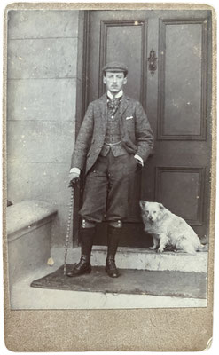 Ein feiner Herr in Knickerbocker mit seinem weißen Spitz vor einer Haustüre. Foto im Carte-de-Visite-Format, vermutlich um die Jahrhundertwende