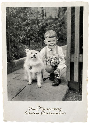 Kleiner Junge mit seinem Spitz auf einer Glückwunschkarte zum Namenstag