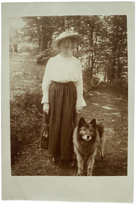 Eine schicke Dame mit Hut und Wolfsspitz