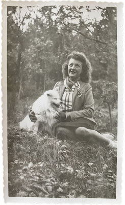 Junge Frau auf einer Wiese sitzend mit ihrem Deutschen Spitz