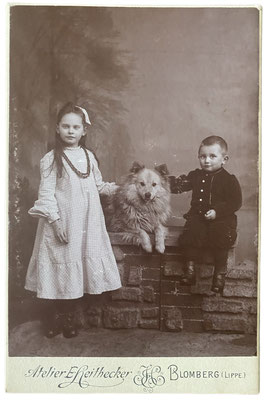 Zwei Kinder mit ihrem Großspitz. Foto aus dem Zeitraum Ende des 19. Jahrhunderts. Atelier E. Heithecker, Blomberg (Lippe)