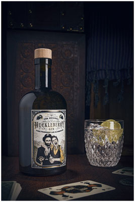 Huckleberry Gin Flasche plus Glas vor dunklem Hintergrund