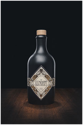 Illusionist Gin Flasche vor dunklem Hintergrund auf Holzplatte