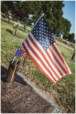 Flagge im Wind auf einem Friedhof – Symbolik von Verlust und Identität.