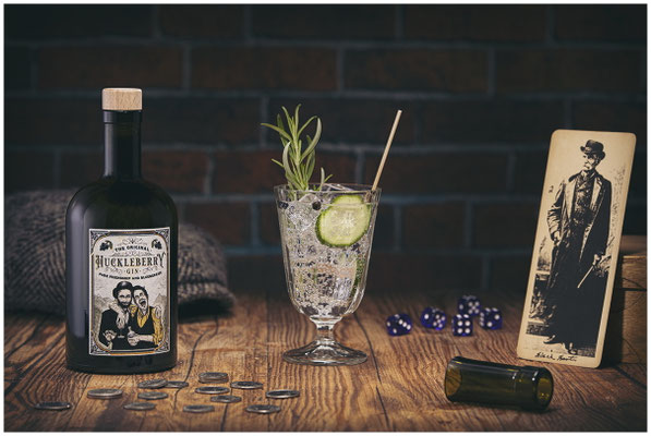 Huckleberry Gin Flasche plus Glas auf Holztisch stilvoll in Szene gesetzt