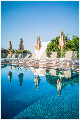 Klarer Pool im Sonnenlicht – Spiegelung von Himmel und Architektur.