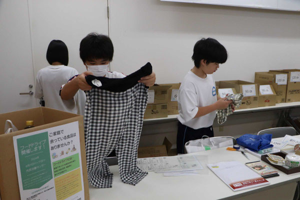 寄付された衣服の整理をする中学生ボランティア