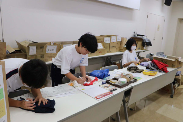 寄付された衣服の整理をする中学生ボランティア