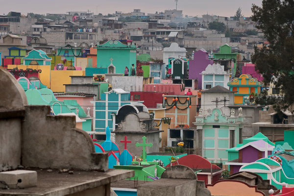 Sumpango cemetary, the bright colours of the cemetary stand in vast contrast to the grey urban sprawl behind it.