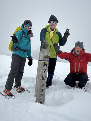 山頂で記念写真、風に吹き飛ばされて雪は少ない