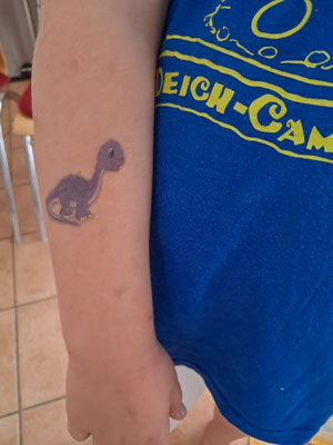 Unterarm eines Kindes mit einem Dinosaurier-Klebetattoo
