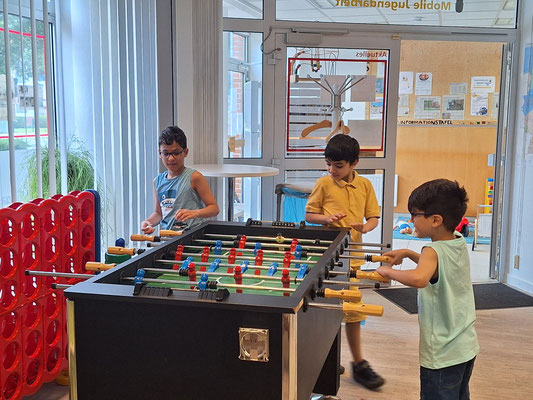 Drei Jungs spielen Kicker.
