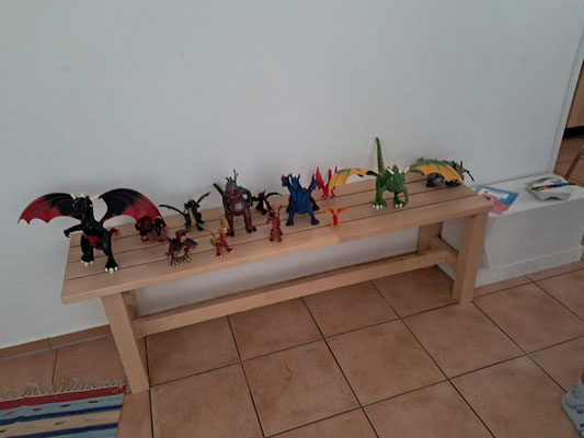 Viele Dino-Spielfiguren stehen auf einer Bank