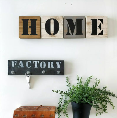 Scrabble mural en bois, gris et blanc avec message d'accueil "Home" accroché dans une entrée avec une plante verte