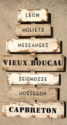 Panneau d'indication en bois vieilli artisanal avec des villes de la côte Ouest comme Seignosse, Messanges ou Moliets