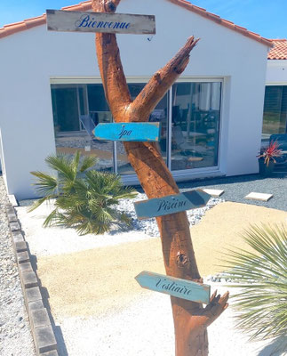 Flèches personnalisées en bois, peintes en bleu et accrochées sur un tronc pour accueillir et guider les hôtes d'un gîte