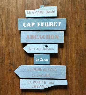 Panneau indicateur personnalisé dans un style bois flotté, avec des lieux-dits autour d'Arcachon, peint dans différents tons de bleu