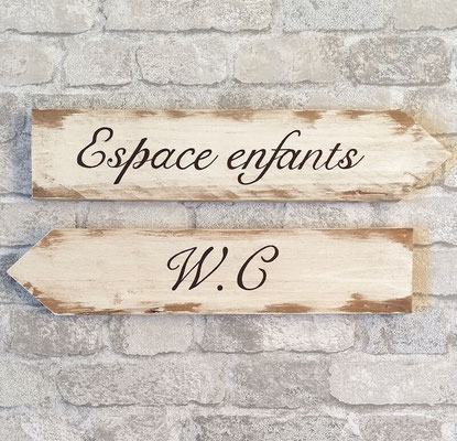 Flèches pour réception bois blanc vieilli sur un mur de briques gris, texte "Espace enfants" et "WC" peint en noir