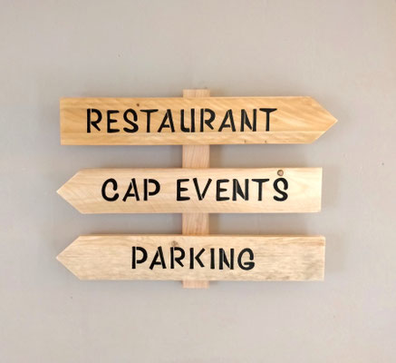 Panneau directionnel en bois brut, indiquant pour accueillir la clientèle le restaurant et le parking de Cap Events