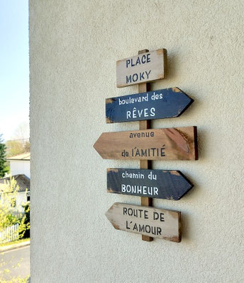 panneau fléché noir, beige et bois accroché sur un balcon, texte personnalisé sur le thème du rêve et du bonheur