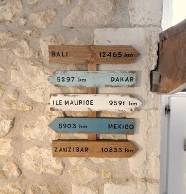 Panneau directionnel bois artisanal accroché sur un mur en pierre pour un cadeau mémorable