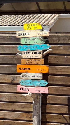 Panneau indicateur dans un jardin, morceaux de bois colorés de taille variés personnalisé de pays comme Maroc, Malaisie ou Grèce peints en noir 