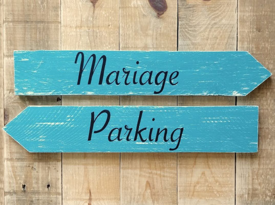 Flèches turquoises patinées posées sur fond bois, pour guider les invités avec les indications de "mariage" et "Parking"