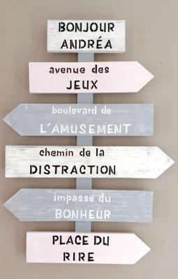 Panneau directionnel fléché rose et gris pour décorer une chambre d'enfant avec des messages comme "avenue des jeux" ou "place du rire"