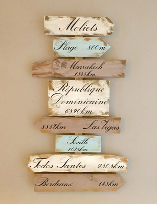  Panneau directionnel en bois blanc, taupe et bleu, personnalisé de destinations comme Marrakech, Las Vegas, Séville calligraphiées sur les flèches