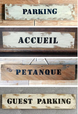 Collage de pancartes en bois recyclé, peinture vieillie dans des tons naturels, indiquant "Parking", "Accueil" et "Réception"