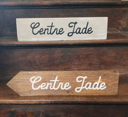 Pancarte peinte en beige et flèche en bois posées dans un escalier, indiquant un centre médical "Centre Jade"