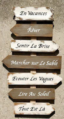 Panneau décoratif fléché avec des phrases positives peintes en noir et blanc posé en extérieur