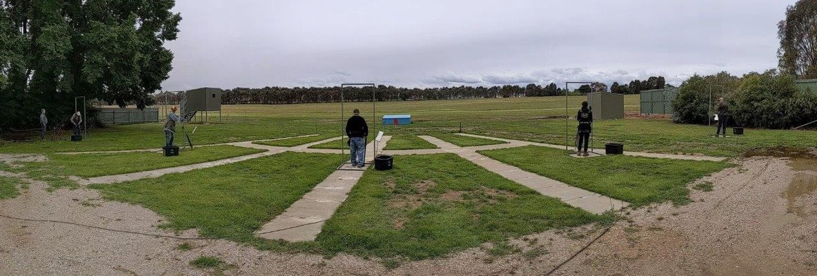 2021 11 13 Bryce, Ernie, Bruce, Ian, Matt and Phil on the Universal Skeet layout. Note that this panorama format distorts the foreground. The shooting pads are straight across the ground, 25m from the target crossing point.