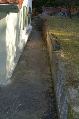 Der Betonweg hinter dem Haus mit Betonstützmauer zum Hang hin vorher 