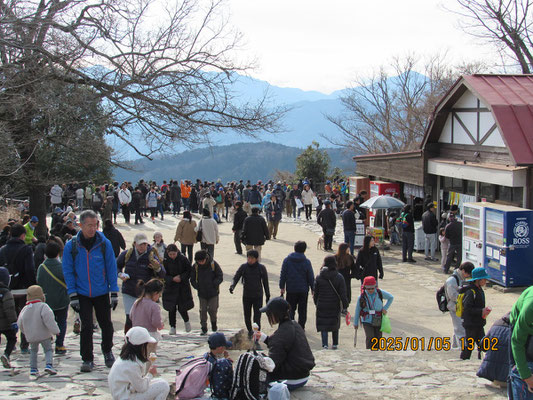 ゴミ拾い1：人混みの高尾山頂で緑色のボランティア袋を持って