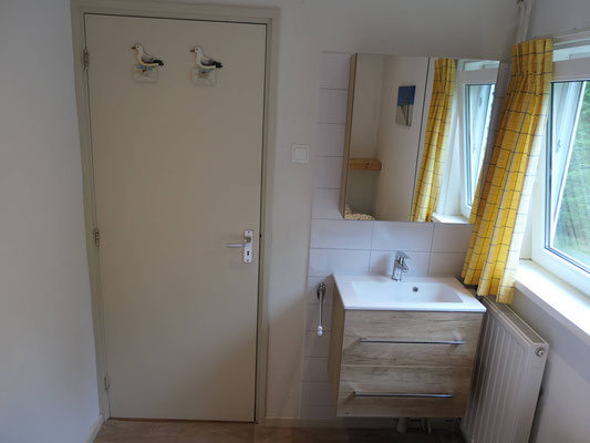 Slaapkamer met wastafel en spiegel van vakantiehuis "Groenoord" op bungalowpark "De Parel", Texel.