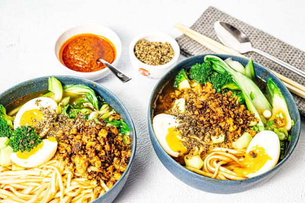 Zwei fertig angerichtete japanische Ramen mit Ei, Pak Choi und hausgemachtem Chili-Öl.