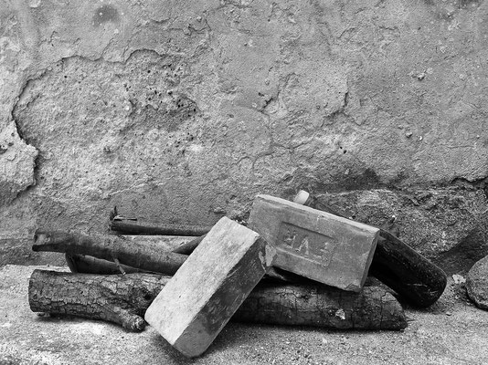 Holz Steine und Flasche vor einer Hauswand, Elba 2005